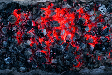 Smoldering burning coal, burnt wood on fire, texture dark background with red glowing coals