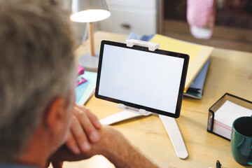 Caucasian man sitting at table in kitchen and using tablet with copyspace