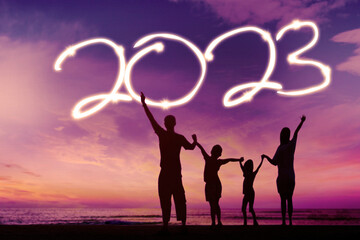 Happy family celebrating new year of 2023 on beach