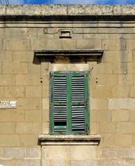 Closed window of the old building covered by green wooden blinds in Rabat town on Malta
