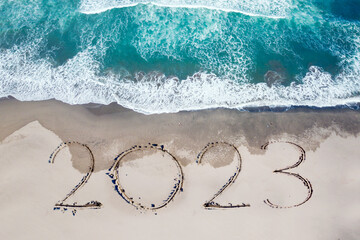2023 numbers written on the sand of coastline