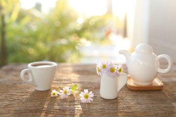 Coffee cup and pot and paris daisy flower on wooden table outdoor
