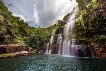 Beautiful waterfall in the middle of the forest softly lit by the sun on a cloudy day