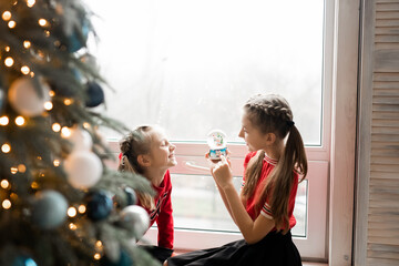 Two sisters on the background of Christmas decorations