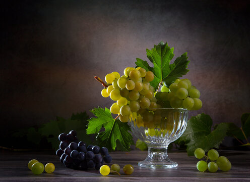 Still life with a bunch of green, red grapes and grape leaves