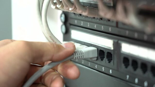 Data center cable. A person inserts a patch cord.
