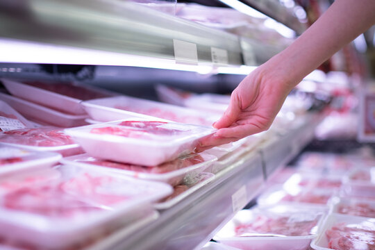 スーパーマーケットでパック入りの肉を手に取る女性の手