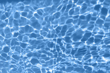Fototapeta na wymiar Defocus blurred transparent blue colored clear calm water surface texture with splash, bubble. Shining blue water ripple background. Surface of water in swimming pool. Blue bubble water shining.