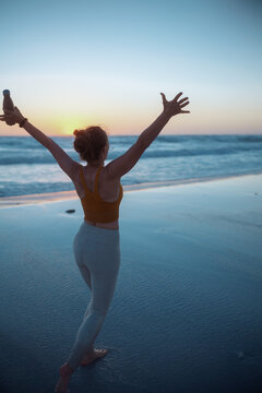 healthy sports woman rejoicing at beach at sunset