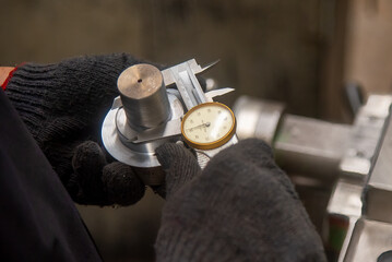 Close up scene the operator measuring outside diameter metal shaft parts by dial Vernier caliper.