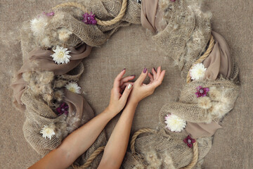 Decorative decoration with flowers on burlap with female hands.