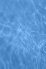 Defocus blurred transparent blue colored clear calm water surface texture with splash, bubble. Shining blue water ripple background. Surface of water in swimming pool. Blue bubble water shining.
