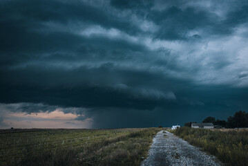 A huge storm cloud with a wall of rain in the countryside.