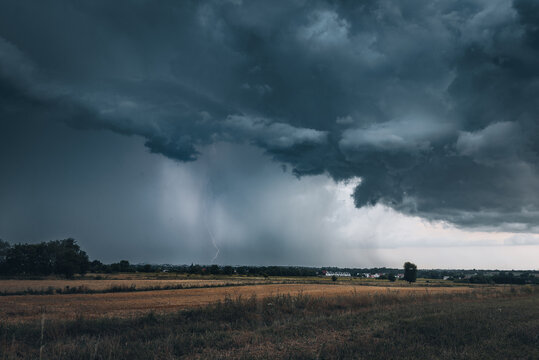 A huge storm cloud with a wall of rain in the countryside.