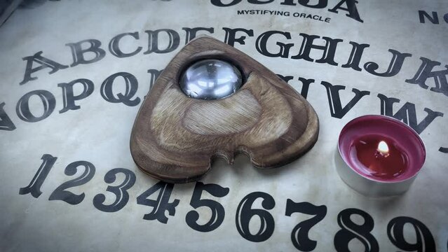 Halloween game with Ouija board. Pointer with magnifying glass and tea red candle on planchette. Scene in haze with smoke. Ghost possesion. Spiritual event. Vintage, retro exposition.