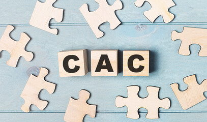 Obraz premium Blank puzzles and wooden cubes with the text CAC Customer Acquisition Cost lie on a light blue background.