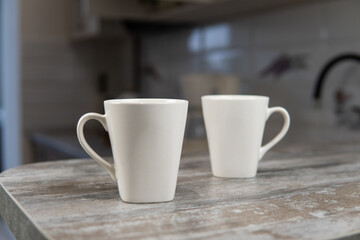 two white mugs stand in the kitchen