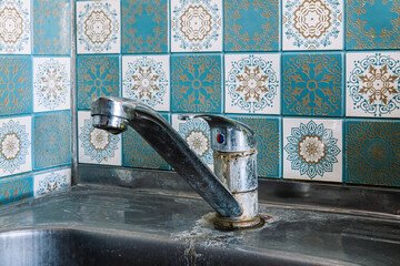 Old rusty sink faucet in kitchen. Rust streaks, calcium scale, hard water. Concept of poor water...