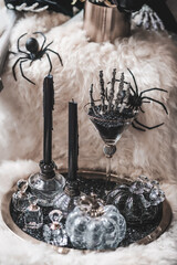 Happy Halloween. A skeleton's hand, black candles and spiders by the window, decoration for Halloween trick or treat party. Processed in black and white with film grained filter.