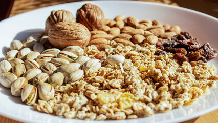 A set of delicious fresh dried fruits - raisins, walnuts, almonds,  pistachios on a white plate isolated
