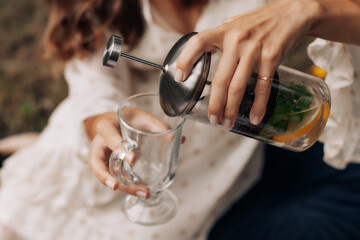 Girl pours tea with lemon into a glass cup