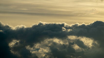 Fluffy yellow clouds after storm going over the horizon. Dark cloudy sky before thunderstorm panoramic background. Storm heaven panorama. Wide gloomy backdrop. Dramatic panorama sky