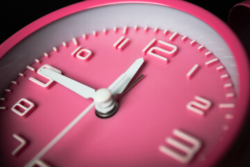 Pink alarm clock setting at fifteen before noon or midnight. Time conceptual.