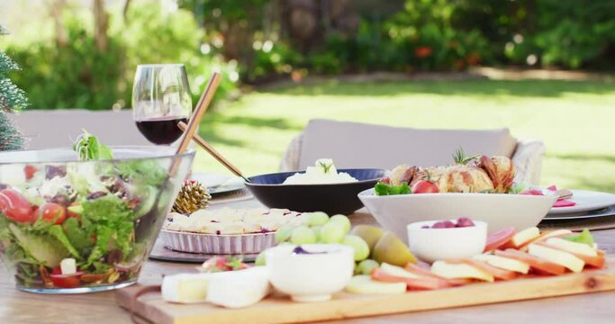 Close up of glass of red wine and food on table in garden