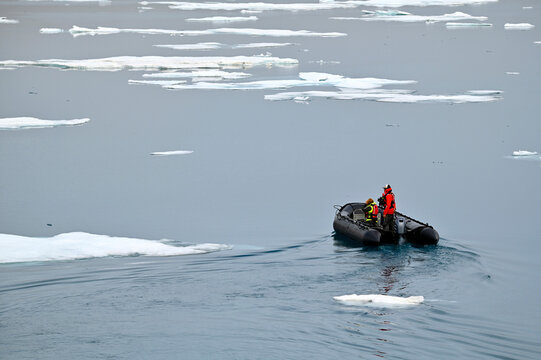 Zodiac boat making its way through the Arctic sea with a floe of melting ice, against picturesque seascape