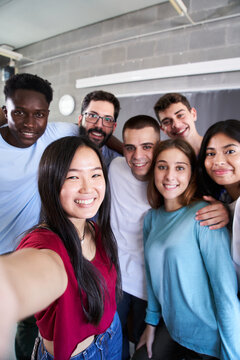 Vertical photo of a multiracial group of friends taking a selfie - New concept of normal friendship with young people looking at the camera and laughing.