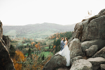 Beautiful gorgeous bride posing to groom and having fun near at mountains with amazing view, space for text, wedding couple