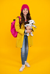Schoolchild, teenage student girl in warm hat with toy on isolated studio background. School and education concept. Back to school. Happy teenager, positive and smiling emotions of teen girl.