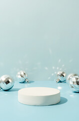 A minimalistic scene of a podium with christmas decorative balls on a light blue background