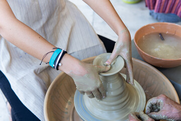 Potters working to shape the clay on the spinning wheel in the workshop. Tanned hands