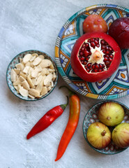 Fresh Mediterranean fruit on a blue ceramic plate. Colorful still life with pomegranate, figs, plums. Healthy eating concept. 