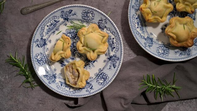 Typical portuguese snack with meat. Chicken pies know as empadas de frango or galinha on old fashioned ceramic plates.