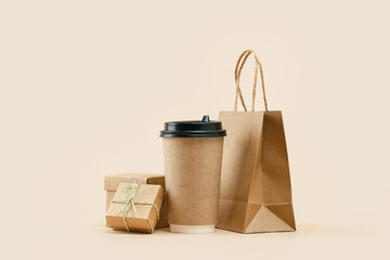 Takeaway paper coffee cup with lunch bag and bonus gift box on beige. Snack delivery service....