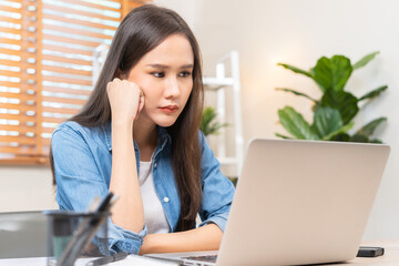 Exhausted, stressed asian young businesswoman working, looking at screen on laptop computer expression face frustrated, suffering on work hard at office. Overtime job, debt problem people.