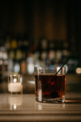 Cocktail on a bar with a votive candle in the background