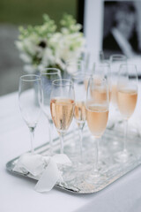 Pink champagne in flutes on a silver tray at a wedding