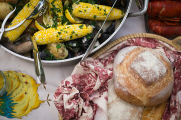 Overhead photo of a clambake on a table with lobster, bread, and corn