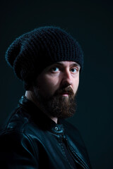 dramatic portrait of bearded millennial guy in leather jacket on dark background