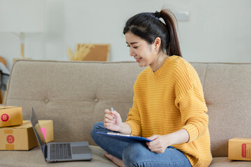 Asian businesswoman using laptop computer online chat with packaging box, Business online influencer on social media concept, Online Selling, Online Shopping to market.