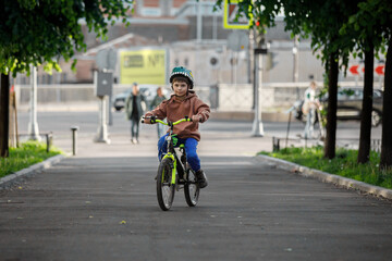 Boy learning to ride bike. Child travels through urban alley