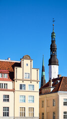 Picturesque Tallinn Town Hall tower and close-up on historic facades of ancient medieval buildings. Daytime, blue sky, historical city center of Tallinn, Estonia.