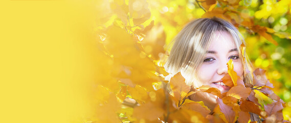 Banner of happy cute smile woman. Girl is on yellow autumnal leafs background. Sunny day. Fall, outdoors. Copy space.