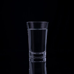 shot glasses with vodka on a black background