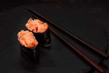 Warm rolls with tuna, salmon, perch, eel, tobiko caviar, nori, rice, cucumber on black background.