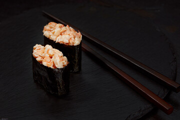 Warm rolls with tuna, salmon, perch, eel, tobiko caviar, nori, rice, cucumber on black background.