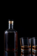 Obraz na płótnie Canvas bottle of strong alcohol brandy with glasses on black background